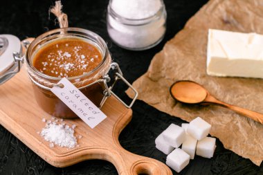 Pişirilmiş tuzlu karamel. Karamel için malzemeler. Kavanozda tuzlanmış karamel..