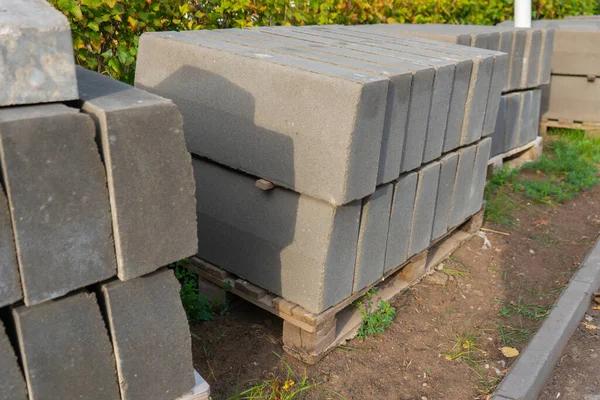 Concrete curbs are stacked on a wooden pallet, construction site