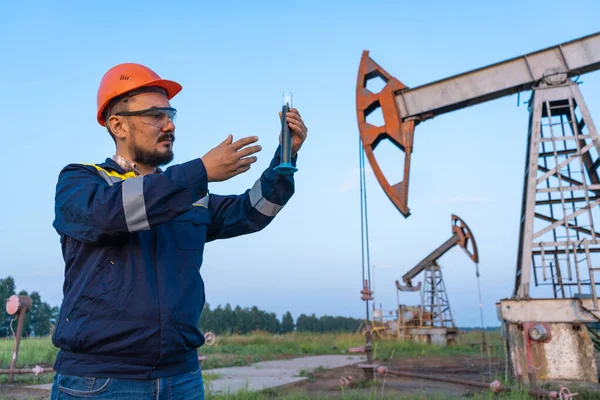 Oil refining. A man takes a sample of oil at an oil field