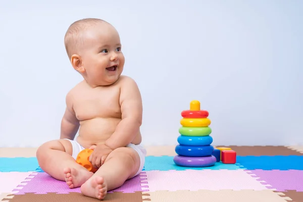 Newborn baby laughs and plays with a rubber ball in the playroom