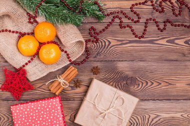 Mandalinalı Noel kompozisyonu, tarçın, yıldız anason, kağıt ve köknar dallarına sarılı hediyeler, ahşap arka planda yeni yıl dekoru. Üst görünüm, alanı kopyala.