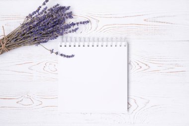 Boş günlükten, bir fincan kahveden, badem kurabiyesinden ve lavanta çiçeklerinden oluşan bir kompozisyon. Moda düzlüğü.