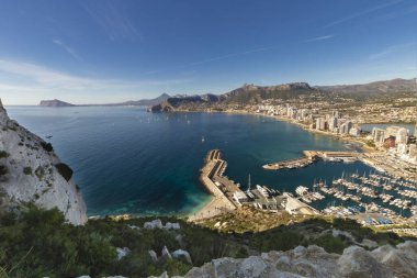 İspanya 'nın Akdeniz kıyısındaki Calpe tatil beldesinde deniz, yat, göl, gökdelenler ve dağ sıraları