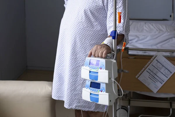 体重過多の男はベッドの背景にドロッパーで立っています 前景にある機器 病院の患者 — ストック写真