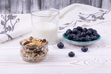 Müsli, süt ve taze yaban mersinli sağlıklı kahvaltı beyaz ahşap bir masa üzerinde, kırsal tarzda, yakın plan, yatay