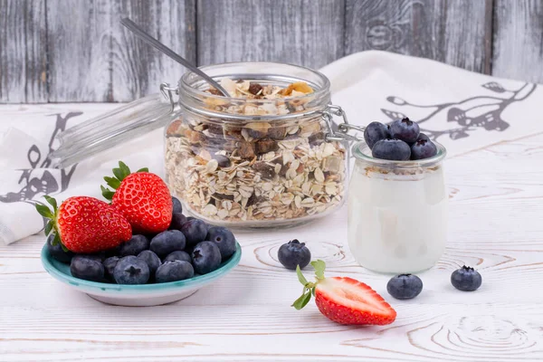 Gesundes Frühstück mit hausgemachtem Joghurt und frischen Erdbeeren und Blaubeeren, Müsli auf weißem Holztisch im rustikalen Stil, Nahaufnahme, waagerecht — Stockfoto