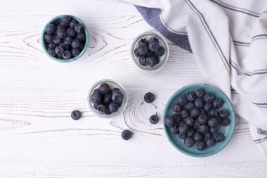 Cam kavanozlarda Yunan yoğurdu ve kırsal beyaz bir masada taze yaban mersini. Düz yat, boşluğu kopyala.