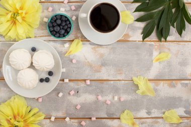 Ahşap arka planda çiçekli kahve ve marşmelov..