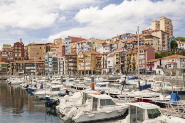 Bermeo, Bask Bölgesi, İspanya - 16 Temmuz 2020: güzel bulutlu bir gökyüzünün zemininde renkli yüzler ve balıkçı tekneleri ile balıkçı limanı.