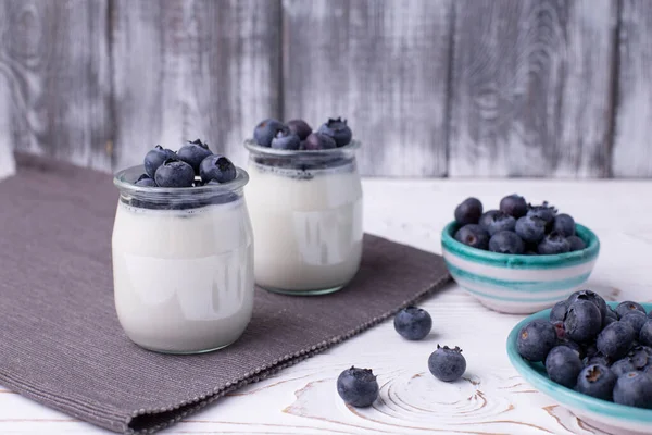 Griechischer Joghurt im Glas und frische Blaubeeren auf einem rustikalen weißen Tisch. Gesundes Essen. Selektiver Fokus — Stockfoto