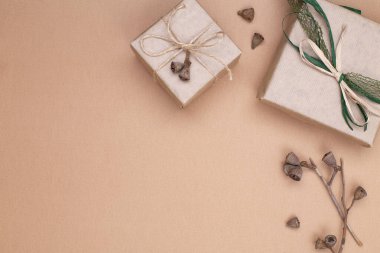 Sonbahar kompozisyonu. Kraft kağıdına sarılı hediyeler, bej arka planda sonbahar okaliptüs yaprakları. Düz konum, üst görünüm, kopyalama alanı.