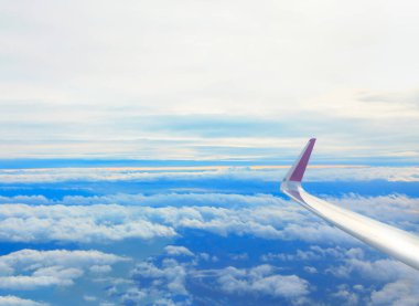 Uçak penceresinden bak. Bulutların üzerinde uçan kanatlar 