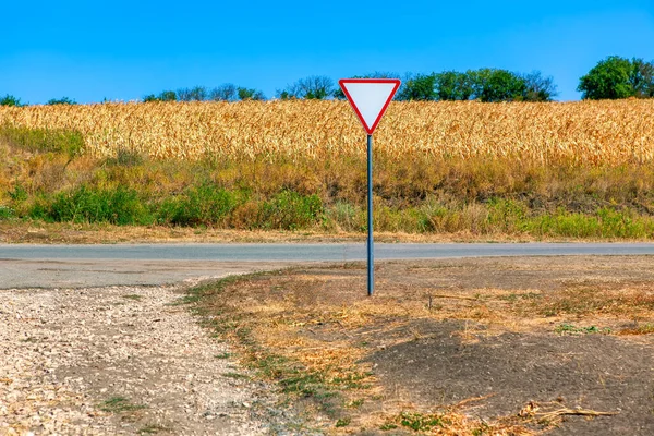 Country road and agricultural field . Road sign give way