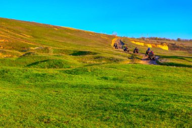 Tepelerde dört tekerli bisiklet sürüyorlar. 