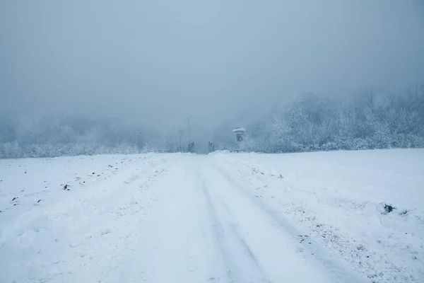 Snowy road in the winter day . Hard road in the Foggy Day