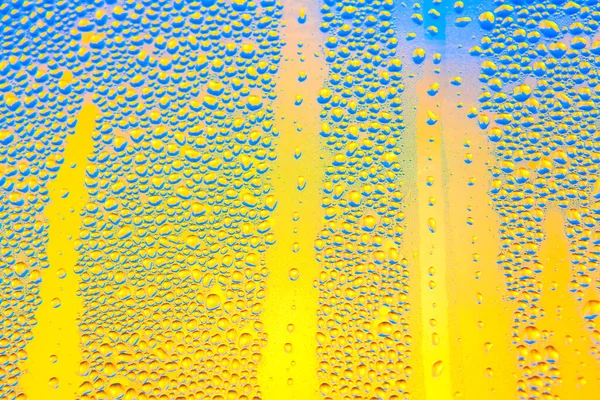 Μπλε Σταγόνες Βροχής Στο Ποτήρι Σταγόνες Κίτρινο Φόντο — Φωτογραφία Αρχείου