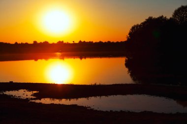 Göl suyunda büyük güneş yansıması. Muhteşem sahil gün batımı. Akşamları balık tutmak. 