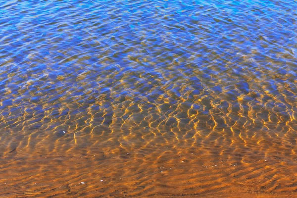 Ripples on the transparent river water . The bottom is visible through clear water