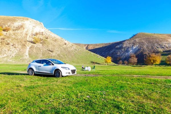 Landscape with white car . Place for picnic at the green meadow