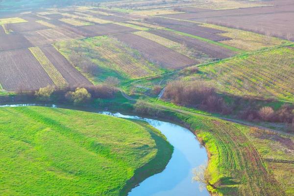 Aerial view of gardens and flowing river . Agricultural fields view from above . Spring nature panorama