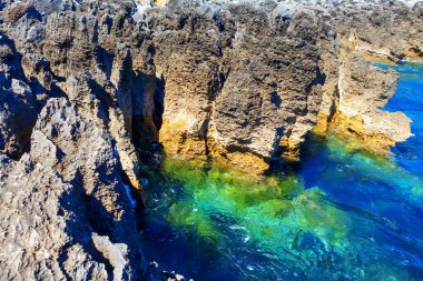 Kıyı kayaları oluşumu ve okyanus turkuaz suyu. Tropikal littoral. Boca do Inferno 'nun okyanus kıyısındaki uçurumları
