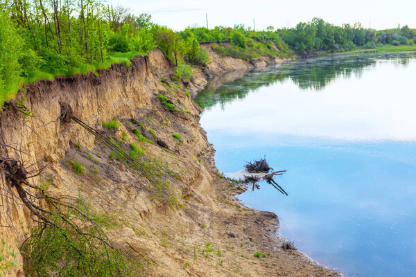 Риверсайд с глиняной скалой. Вихревая река. Обнаженные корни деревьев после оползня