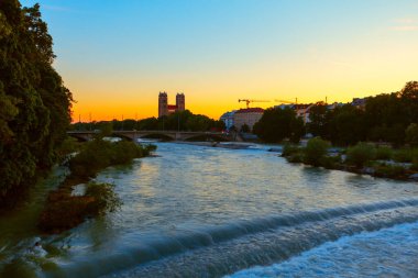 Akşam saatlerinde Münih 'te Isar nehri. Reichenbachbrucke ve Kath 'ın manzarası. Pfarramt St. Maximilia