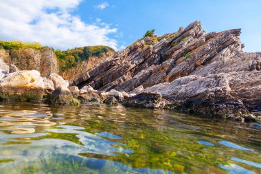 Shale kıyı şeridi ve şeffaf deniz suyu. Idyllic deniz kenarı doğa ve kayalar