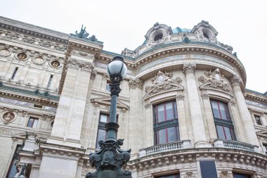 Palais Garnier 'in dışı, Paris' in tarihi opera binası, Beaux-Arts tarzı. Ayrıntılı cephesinin önünde duran bir sokak lambası.