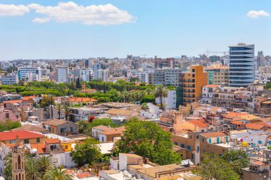 Kıbrıs Rum Kesimi 'nin Lefkoşe kentinin havadan görünüşü, açık mavi gökyüzü altında geleneksel binalarla modern gökdelenlerin bir karışımını sergiliyor. Şehir manzarası başkentin eşsiz mimari tarihini vurguluyor