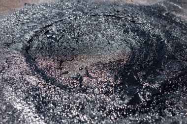 Çatı tamiri devam ediyor, yeni yerleştirilmiş parlak siyah asfalt dolgu maddesi hasarlı kiremitlere sızıntıları önlemek için uygulandı. Koyu grideki desenli çatı malzemesi ve ince örtüşmeler. 