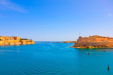 Malta 'nın tarihi büyük limanı, özellikle St. Angelo Kalesi ve güçlendirilmiş Birgu şehri sergileniyor. Akdeniz gökyüzü ve siperlerin kireçtaşı mimarisiyle çelişen derin mavi sular.