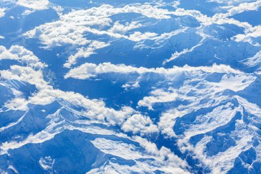 Karla kaplı dağ sırasının havadan görünüşü, Kanada, British Columbia 'daki Rocky Dağları. Bulut katmanlarının üzerinde yükselen dramatik, engebeli zirveler bulut tepkisi olarak bilinen fenomen, yüksek irtifada uçak