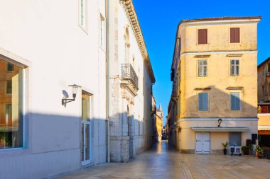 Hırvatistan 'ın Zadar kentindeki eski bir caddede. Gökyüzü altındaki modern tasarım odaları ve tarihi binalar arasında cilalanmış taş kaldırımlar var. Parlak tarihi binaların yer aldığı dar Avrupa sokak manzarası