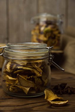 Ev yapımı kavrulmuş, kurutulmuş organik elma dilimleri. Kahverengi ahşap zemin üzerinde cam kavanozda baharat bulunan elma cipslerini metin için kopyalama alanı ile kapat