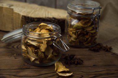 Ev yapımı kavrulmuş, kurutulmuş organik elma dilimleri. Kahverengi ahşap zemin üzerinde cam kavanozda baharat bulunan elma cipslerini metin için kopyalama alanı ile kapat