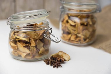 Ev yapımı kavrulmuş, kurutulmuş organik elma dilimleri. Cam kavanozda baharat olan elma cipslerini beyaz arkaplanda izole edilmiş ve metin için kopyalama alanı olan kapat