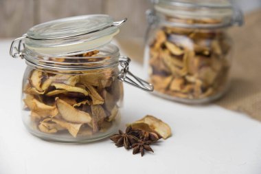 Ev yapımı kavrulmuş, kurutulmuş organik elma dilimleri. Cam kavanozda baharat olan elma cipslerini beyaz arkaplanda izole edilmiş ve metin için kopyalama alanı olan kapat