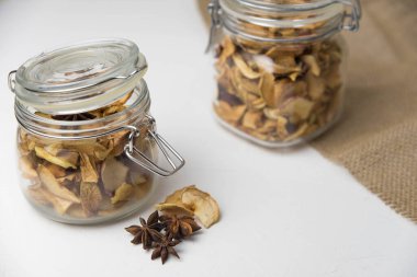 Ev yapımı kavrulmuş, kurutulmuş organik elma dilimleri. Cam kavanozda baharat olan elma cipslerini beyaz arkaplanda izole edilmiş ve metin için kopyalama alanı olan kapat