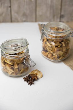 Ev yapımı kavrulmuş, kurutulmuş organik elma dilimleri. Cam kavanozda baharat olan elma cipslerini beyaz arkaplanda izole edilmiş ve metin için kopyalama alanı olan kapat