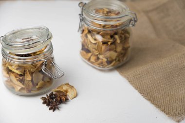 Ev yapımı kavrulmuş, kurutulmuş organik elma dilimleri. Cam kavanozda baharat olan elma cipslerini beyaz arkaplanda izole edilmiş ve metin için kopyalama alanı olan kapat