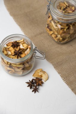 Ev yapımı kavrulmuş, kurutulmuş organik elma dilimleri. Cam kavanozda baharat olan elma cipslerini beyaz arkaplanda izole edilmiş ve metin için kopyalama alanı olan kapat