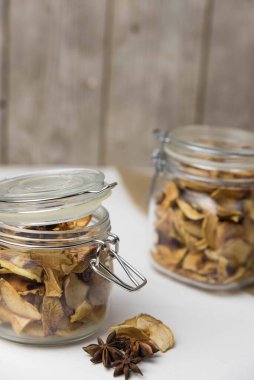 Ev yapımı kavrulmuş, kurutulmuş organik elma dilimleri. Cam kavanozda baharat olan elma cipslerini beyaz arkaplanda izole edilmiş ve metin için kopyalama alanı olan kapat