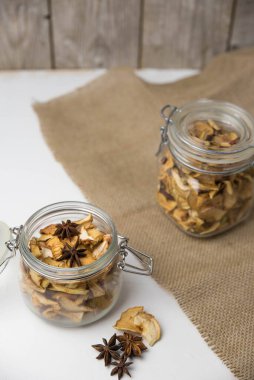 Ev yapımı kavrulmuş, kurutulmuş organik elma dilimleri. Cam kavanozda baharat olan elma cipslerini beyaz arkaplanda izole edilmiş ve metin için kopyalama alanı olan kapat