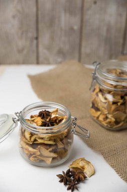 Ev yapımı kavrulmuş, kurutulmuş organik elma dilimleri. Cam kavanozda baharat olan elma cipslerini beyaz arkaplanda izole edilmiş ve metin için kopyalama alanı olan kapat