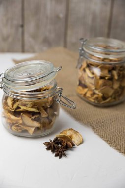 Ev yapımı kavrulmuş, kurutulmuş organik elma dilimleri. Cam kavanozda baharat olan elma cipslerini beyaz arkaplanda izole edilmiş ve metin için kopyalama alanı olan kapat