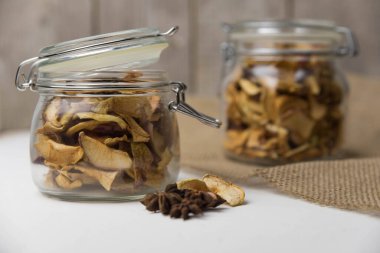 Ev yapımı kavrulmuş, kurutulmuş organik elma dilimleri. Cam kavanozda baharat olan elma cipslerini beyaz arkaplanda izole edilmiş ve metin için kopyalama alanı olan kapat