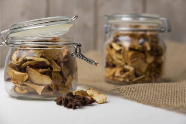 Ev yapımı kavrulmuş, kurutulmuş organik elma dilimleri. Cam kavanozda baharat olan elma cipslerini beyaz arkaplanda izole edilmiş ve metin için kopyalama alanı olan kapat