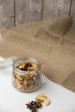 Ev yapımı kavrulmuş, kurutulmuş organik elma dilimleri. Cam kavanozda baharat olan elma cipslerini beyaz arkaplanda izole edilmiş ve metin için kopyalama alanı olan kapat