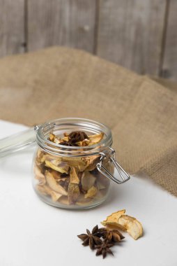 Ev yapımı kavrulmuş, kurutulmuş organik elma dilimleri. Cam kavanozda baharat olan elma cipslerini beyaz arkaplanda izole edilmiş ve metin için kopyalama alanı olan kapat